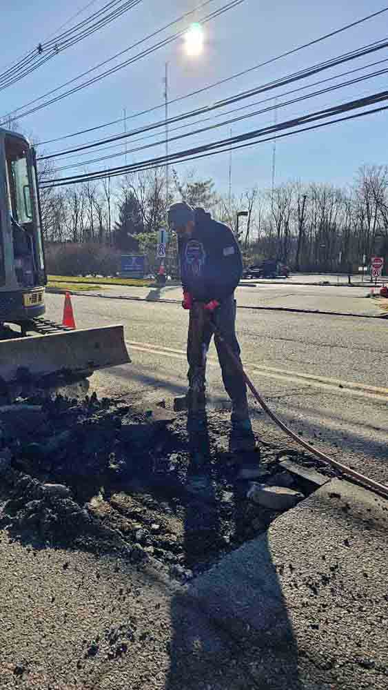 Worker performing commercial sewer services in Bound Brook, NJ, using equipment to excavate a trench on a sunny day, showcasing plumbing expertise and commitment to quality service.