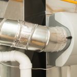 Metal ventilation duct system showcasing curved metallic ductwork and plastic components for efficient airflow management.