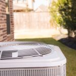 Close-up of a modern air conditioning unit on grass, highlighting energy-efficient solutions by Jeffrey Burke Plumbing.