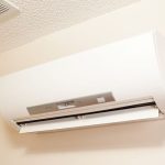 Wall-mounted air conditioning unit with white exterior and metallic control panel for energy-efficient home comfort.
